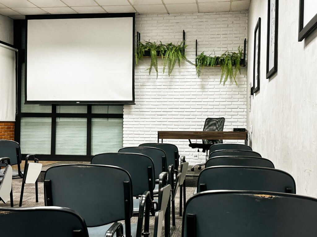 Auditorio com mesas organizadas e tela de projeção