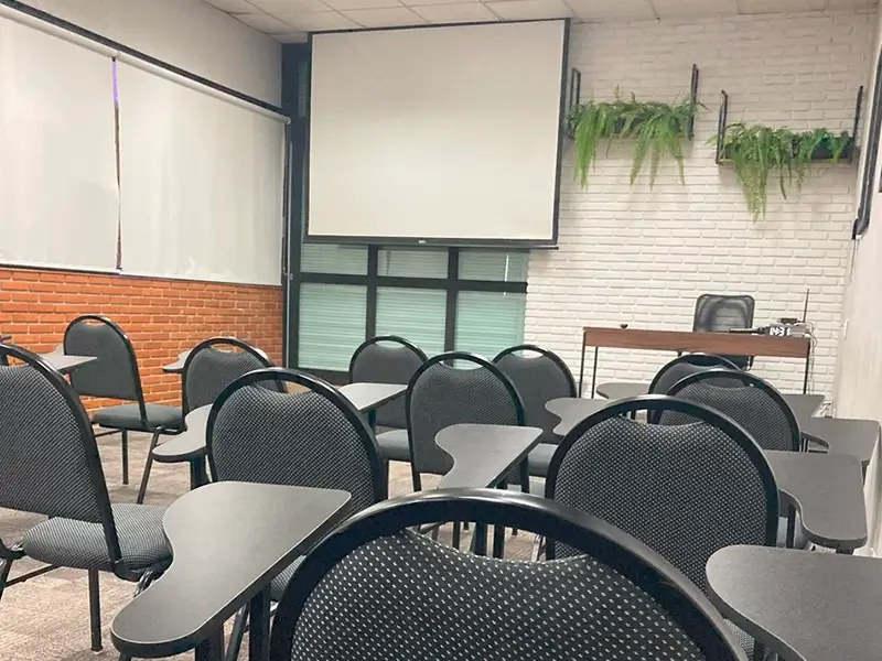 Auditorio com cadeiras universitarias e tela de projeção